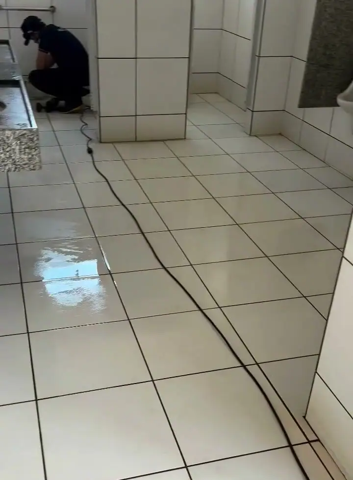 Profissional da Facilitta Clean terminando a limpeza de um banheiro coletivo